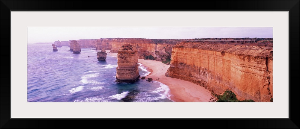 Pano of the Twelve Apostles sticking out of the Tasman Sea as the waves crash on to the sandy shore and the cliffs of shor...