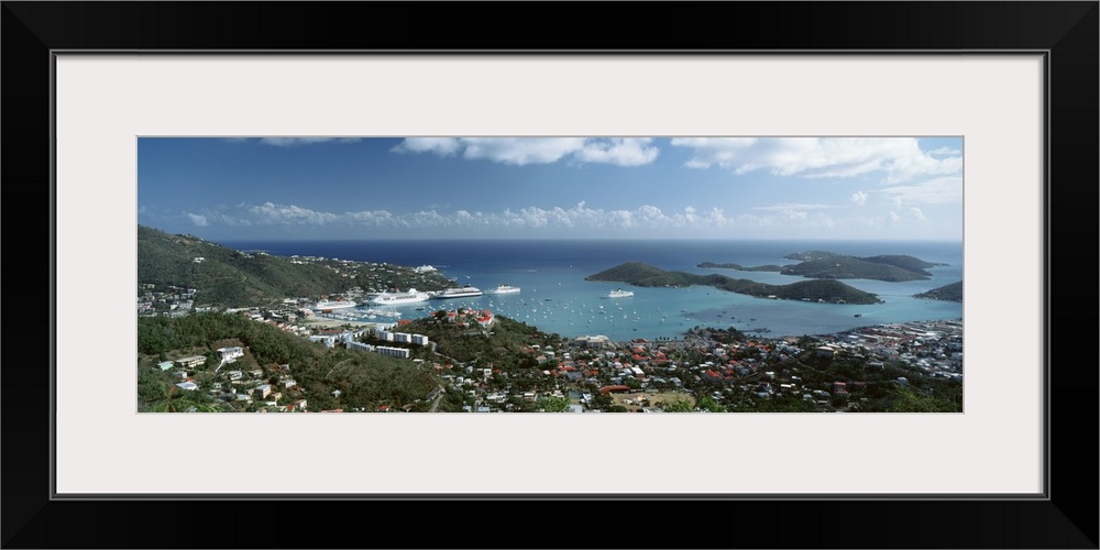 Panoramic photograph of aerial view of city near water's edge under a cloudy sky.