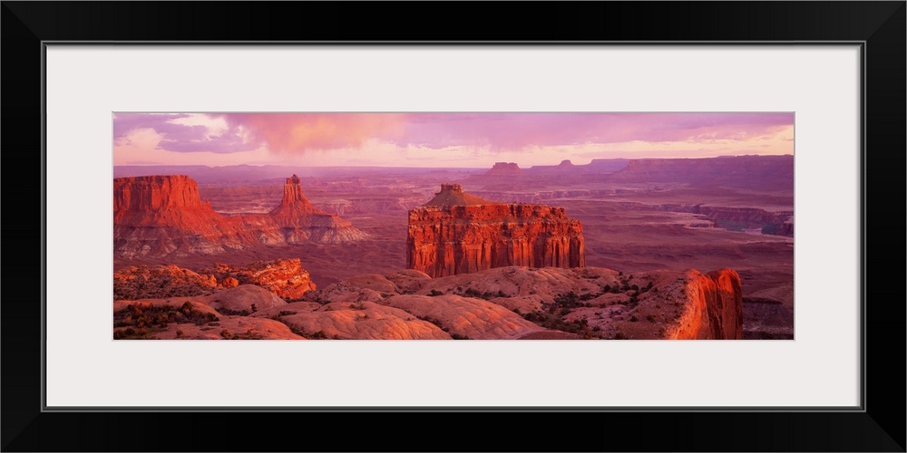 Wide angle, aerial photograph of the rocky terrain at Canyonlands National Park in Utah, beneath a pastel sky.