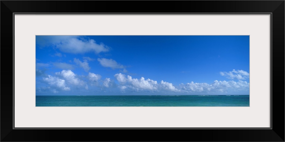 Panoramic photograph of ocean under a cloudy sky.