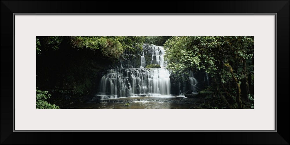 Wide angle photograph of green trees and foliage surrounding Purakaunui Falls in the Catlins, on South Island, New Zealand.