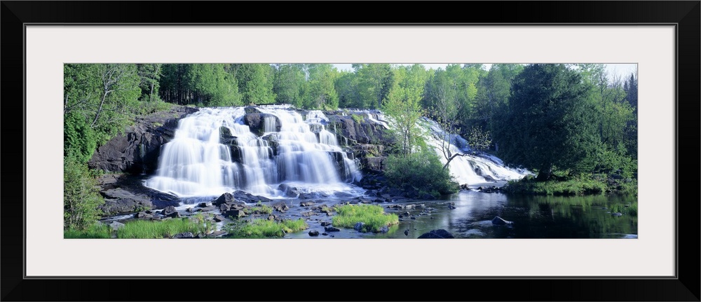 Panoramic photograph on a giant wall hanging of a wide waterfall surrounded by a lush, green forest of trees, in Michigan.