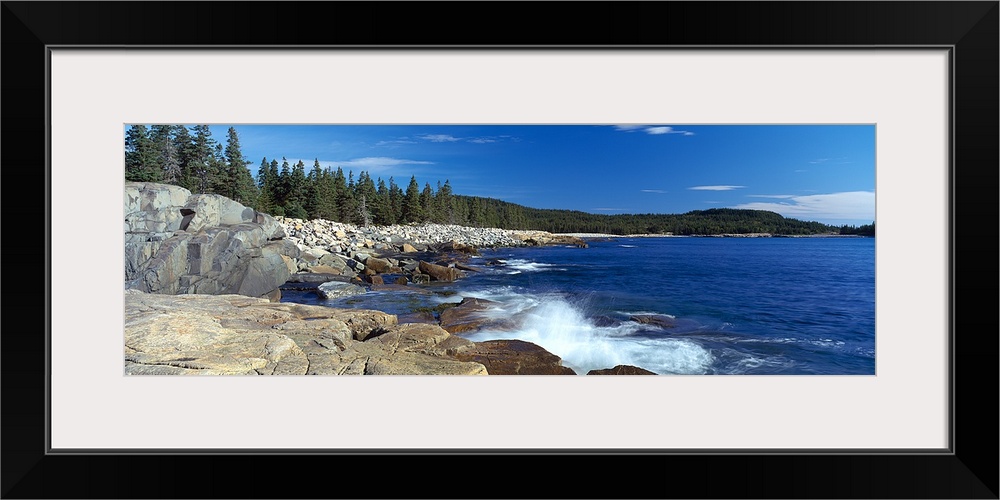 Rocky shore in New England near a pine forest, with fresh water from the Atlantic bay splashing on the stones.