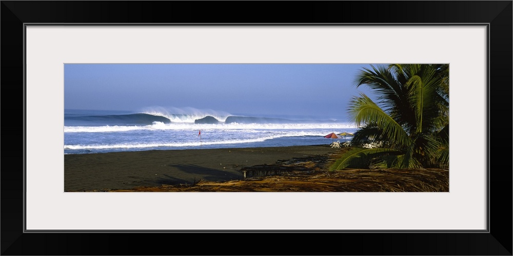 Panoramic photograph taken of a large wave as it begins to break in the ocean. The picture is taken from behind a straw hu...