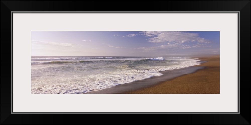 A wide angle picture of the ocean as the water begins to rush up on the warm sand.