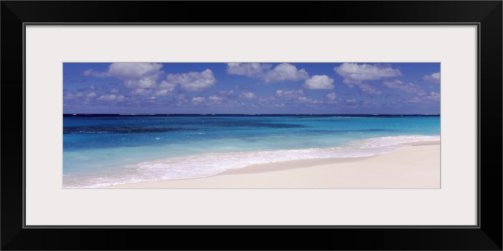 Panoramic photograph of the ocean against the sand on a cloudy day at Shoal Bay Beach in Anguilla.