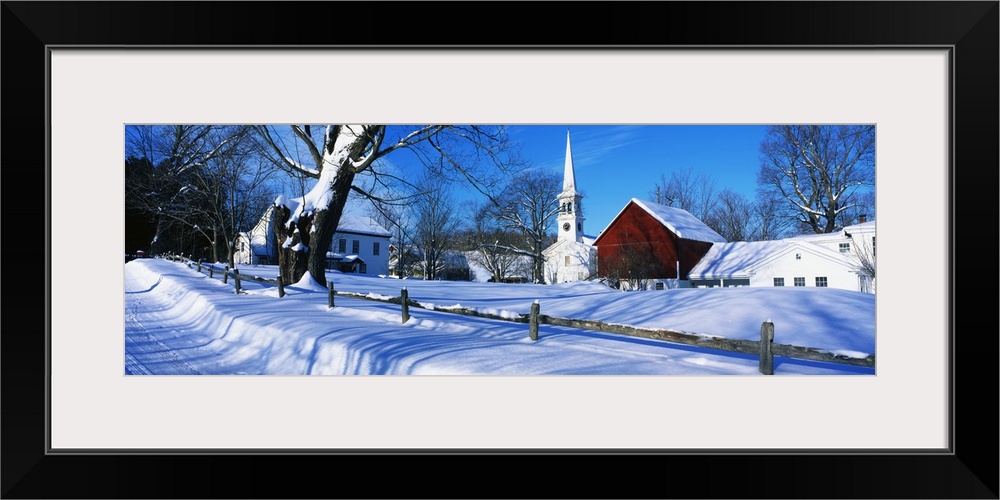 Large, horizontal photograph of a snow covered landscape next to the road in Peacham, Vermont.  Several buildings can be s...