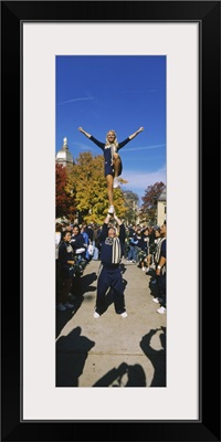 Woman standing one leg on a man hand and performing a stunt, University Of Notre Dame, South Bend, Indiana