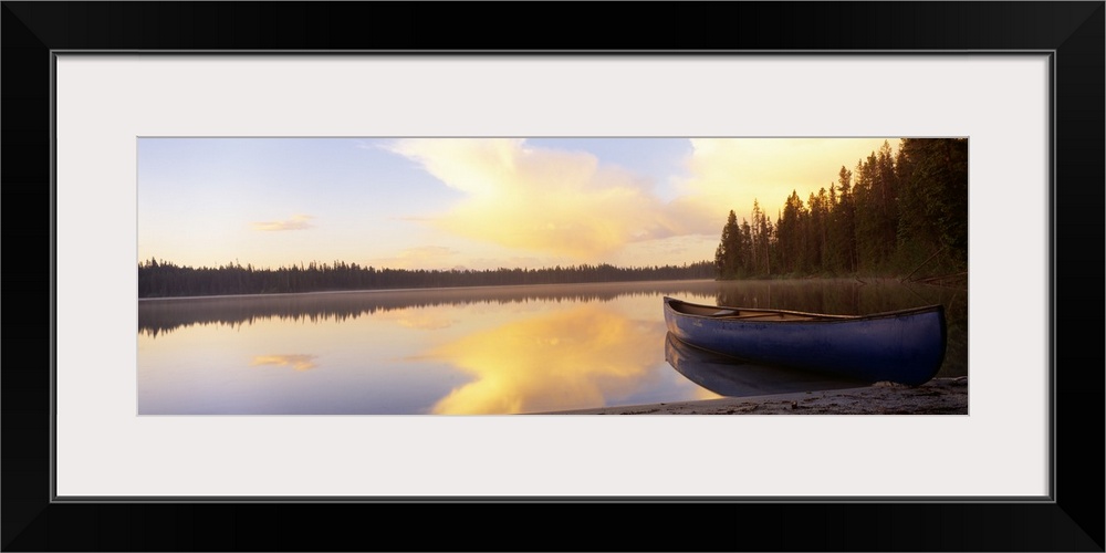 Oversized landscape photograph of a partly cloudy sky and distant tree line, reflecting over the waters of Leigh Lake, a b...