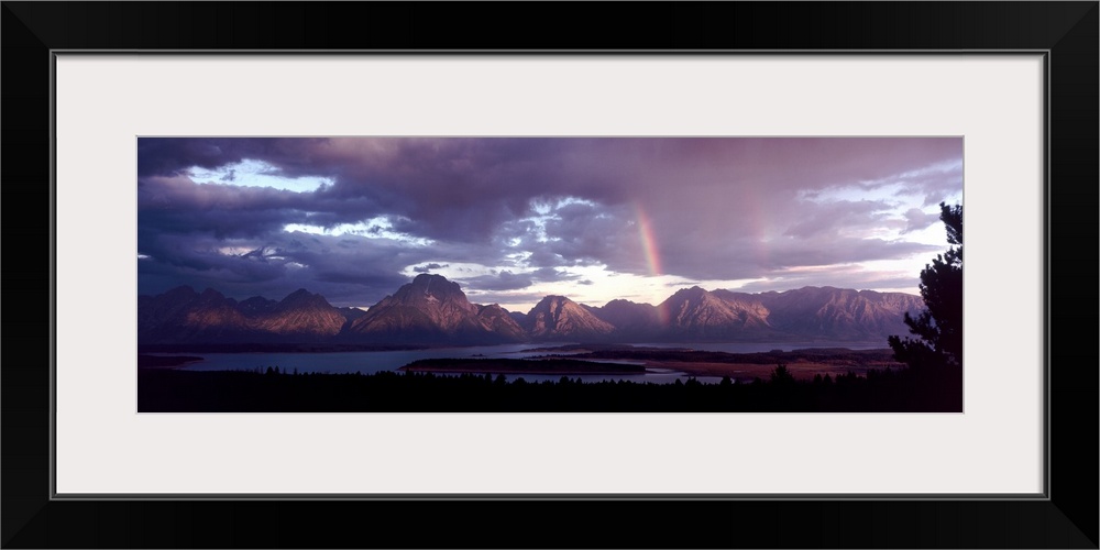 Storm clouds clearing over a lake near the Grand Teton mountain range in the central United States.