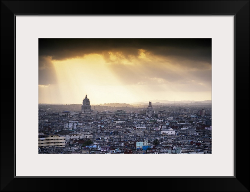 Photograph of the sunrise over Havana, Cuba with large sun beams peering though the clouds and onto the city.