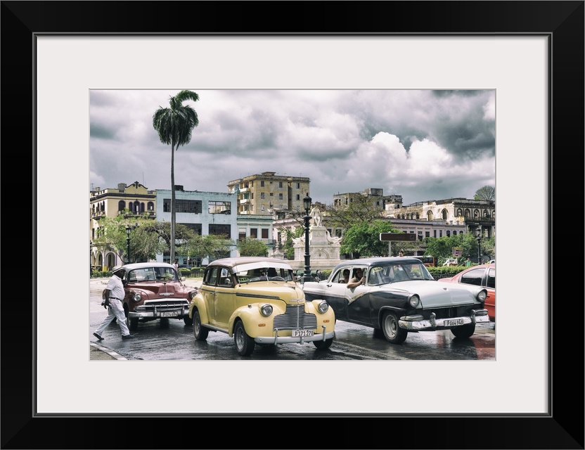 Photograph of dramatic rain clouds above a Havana street scene with vintage cars and taxis.