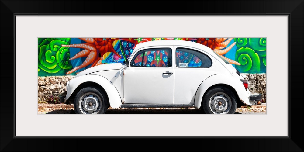 Panoramic photograph of a classic white Volkswagen Beetle parked in front of a colorful wall full of graffiti in Cancun, M...