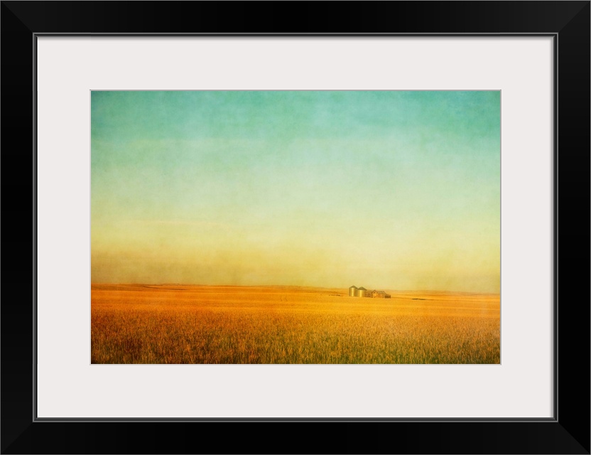 A fine art pictorialist photograph of a ripening wheat field on the Canadian prairies during sunset. An old prairie buildi...