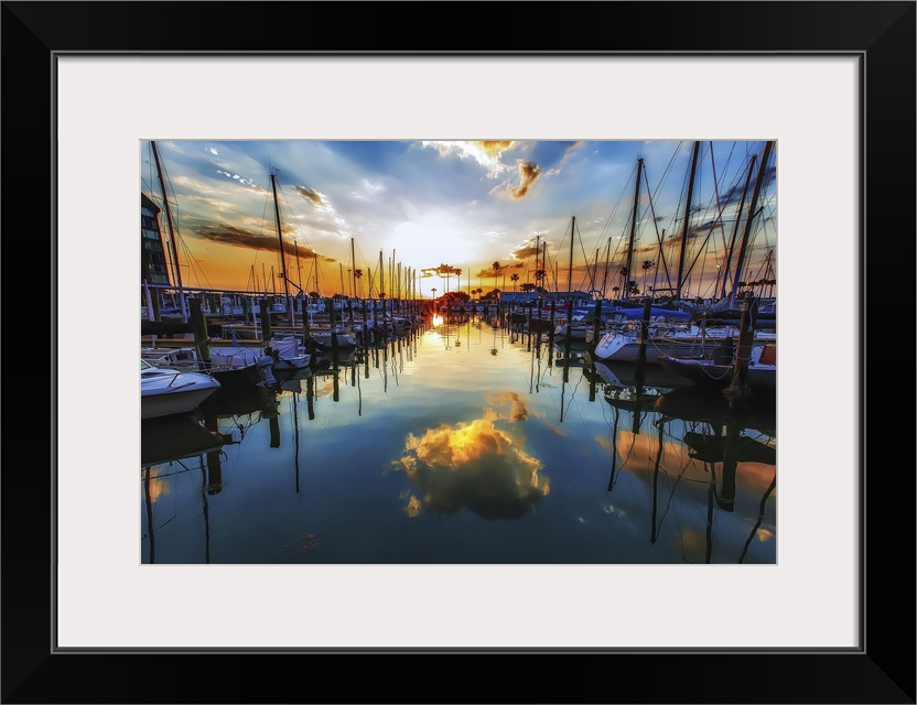 Sailboats in a harbor casting perfect reflections in the water below.