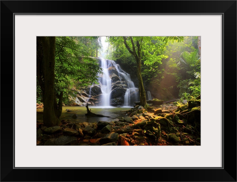 Photograph of a Malaysian forest with a view of a waterfall falling down over top of rocks.