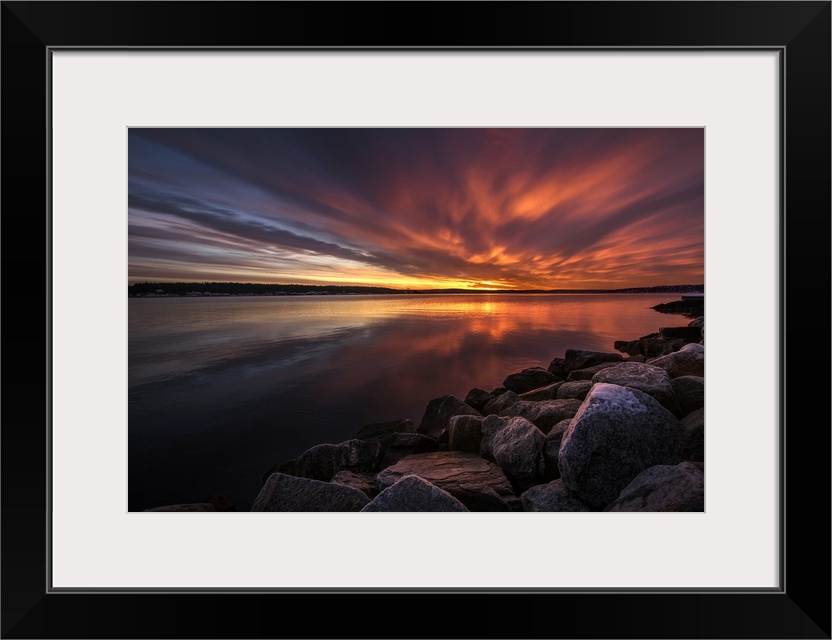 Beautiful sunset colors and dramatic clouds over a rocky beach.