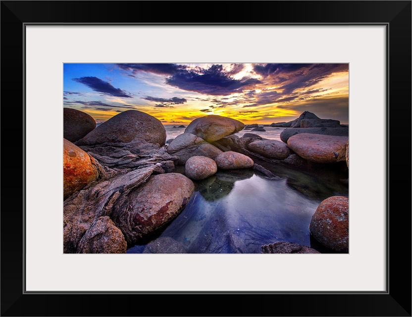 Beautiful sunset colors and dramatic clouds over a rocky beach.