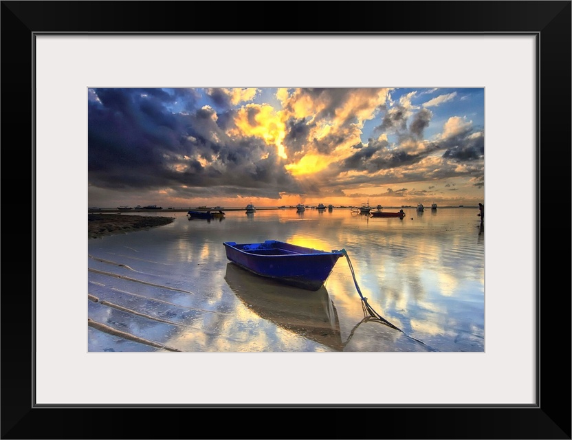 A blue boat docked in shallow water at sunrise, Semawang Beach, Bali.