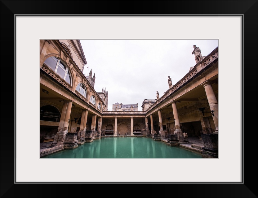 Photograph of the Great Bath in England with gray, cloudy skies above, Bath, England, UK