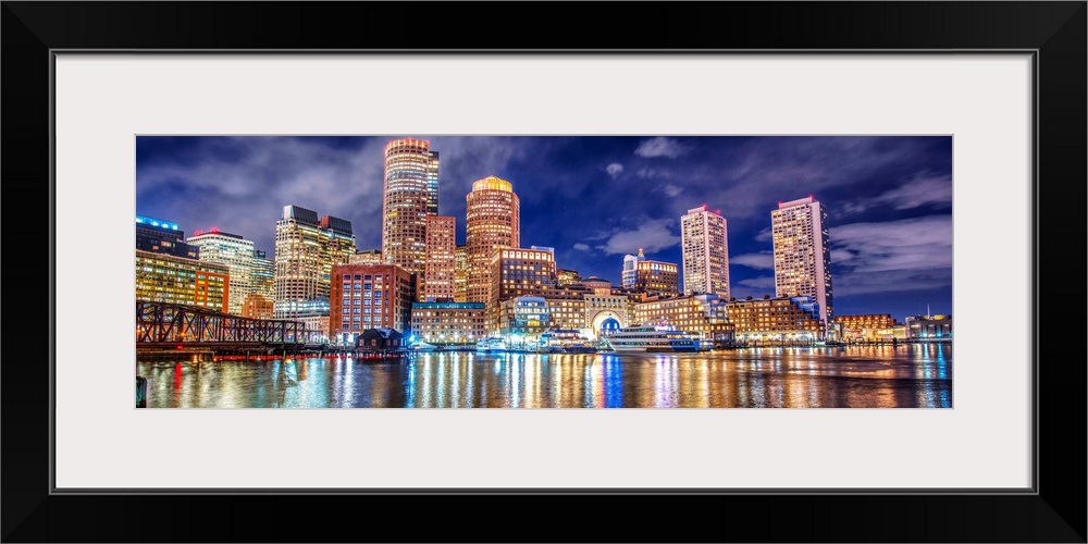 Panoramic view of the Boston City skyline at night, with lights reflected in the water.