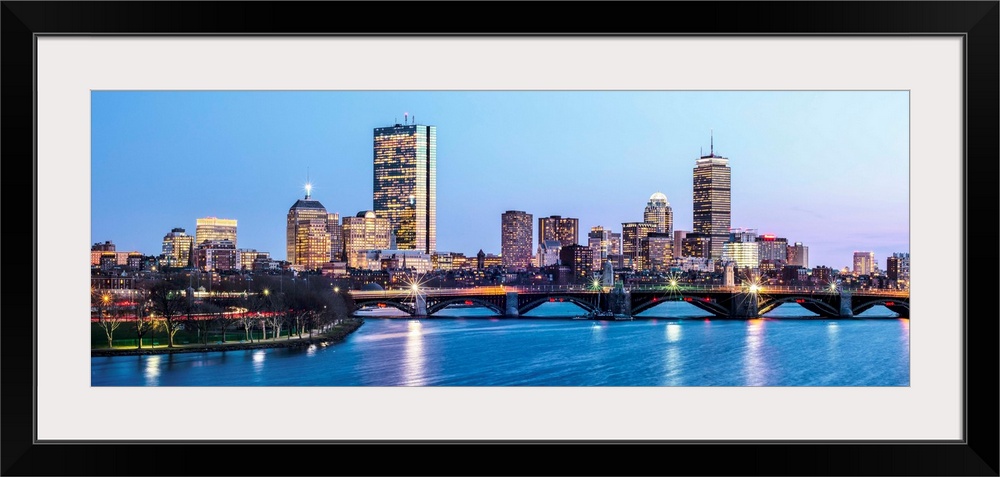 Panoramic view of the Boston City skyline illuminated at night, with the Longfellow Bridge in the foreground.