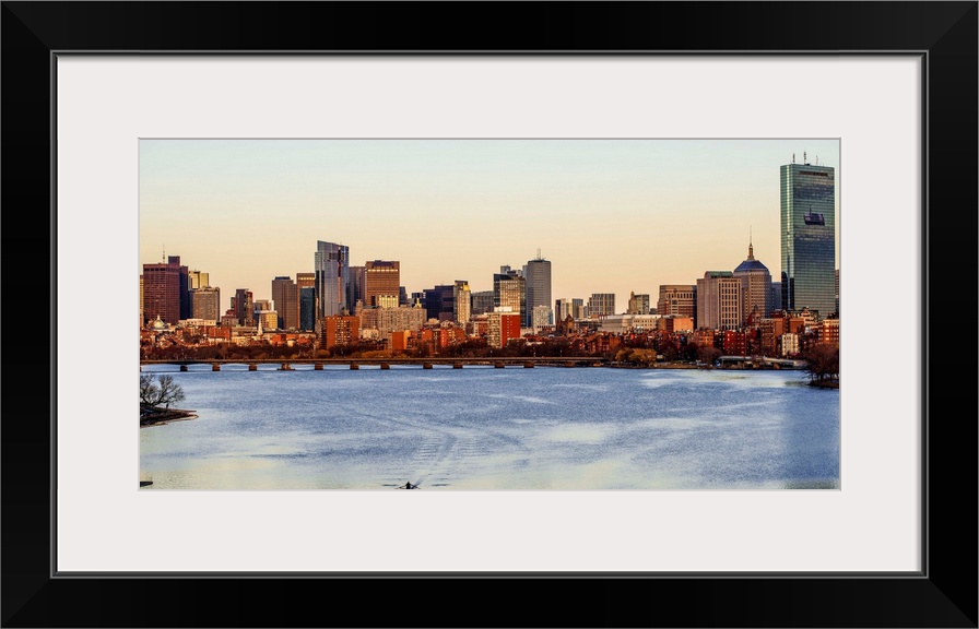 Panoramic view of the Boston City skyline at sunset, seen from across the water.