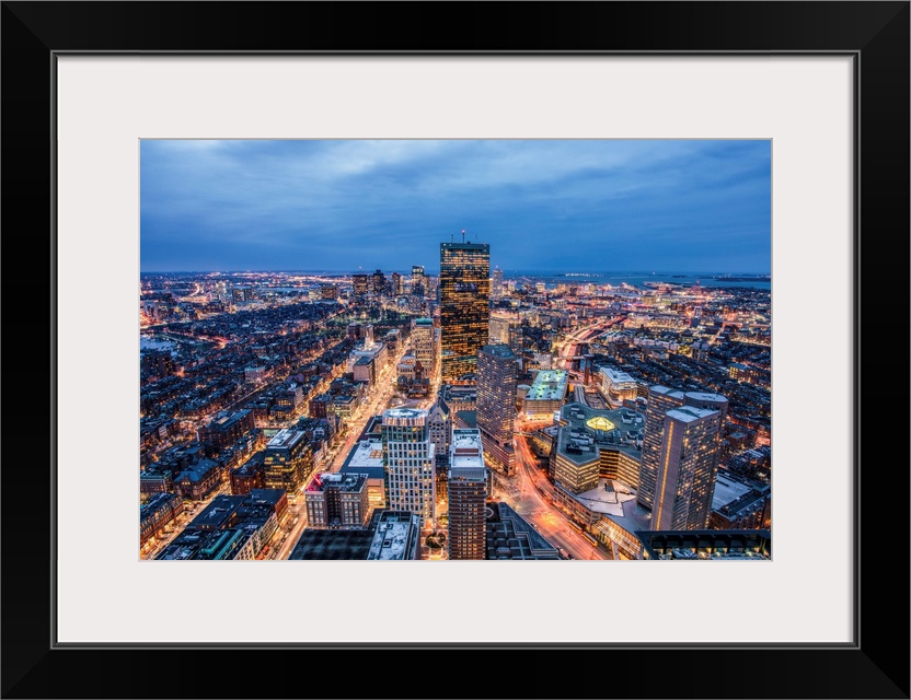 View from a skyscraper of tall buildings in Boston glowing at night.