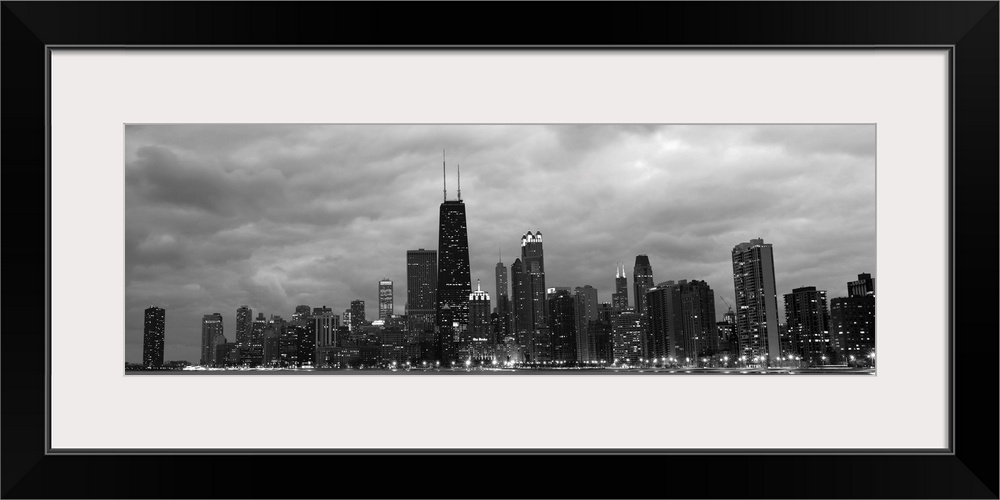 Panoramic view of the Chicago city skyline illuminated in the early evening, seen from across the water.