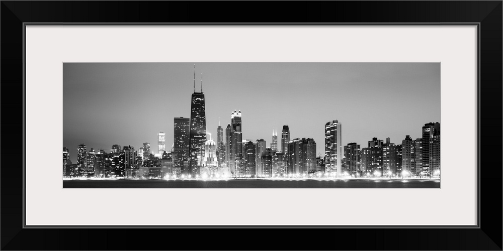 Panoramic view of the Chicago city skyline illuminated in the early evening, seen from across the water.