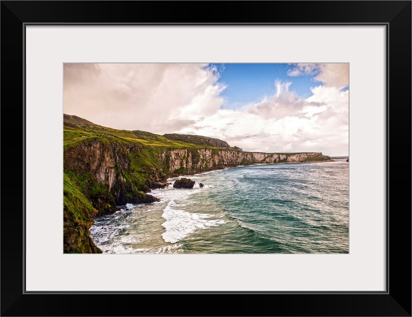 Landscape photograph of the picturesque Cliffs of Moher with a cloudy sky above, located at the southwestern edge of the B...