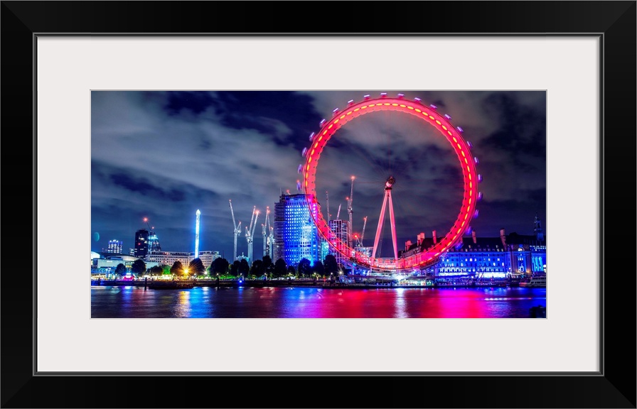 View of the brightly colored ferris wheel at night in London, England.