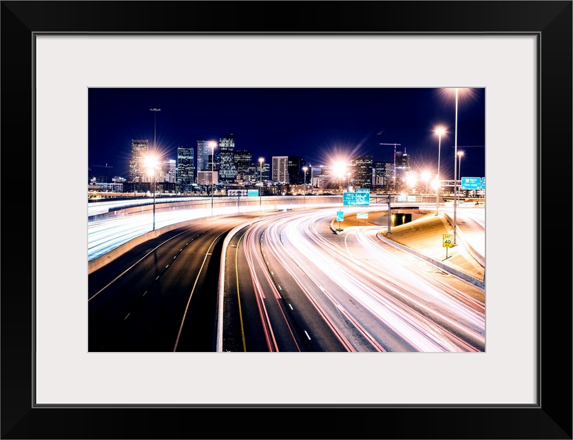 Photo of light trails against Denver's night skyline.