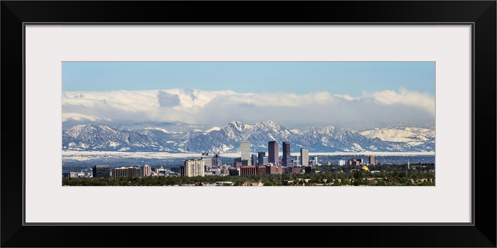 Panoramic photo of a Denver skyline against a backdrop of the Rocky Mountains.