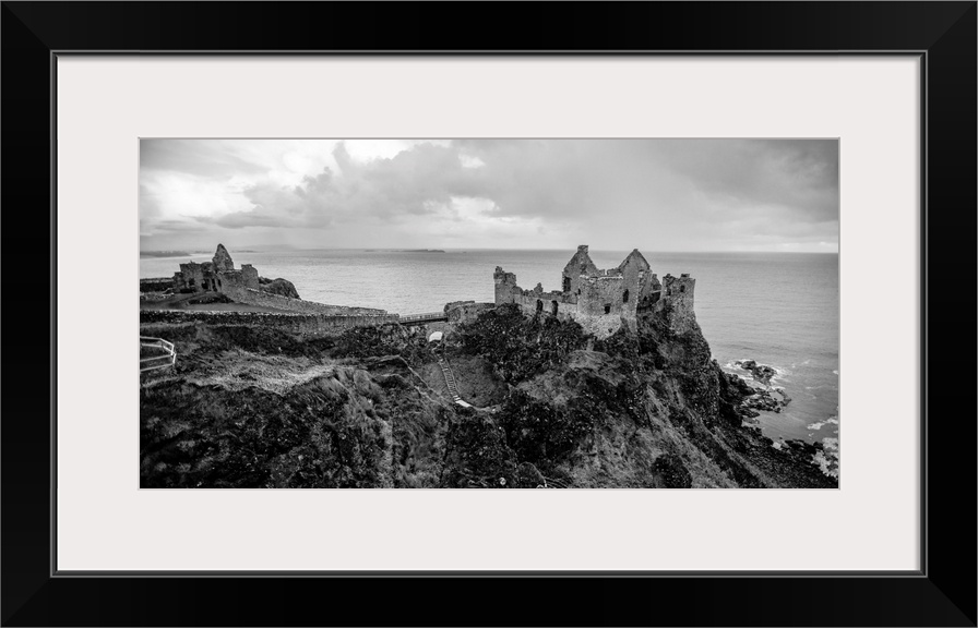 Landscape photograph of Dunluce Castle next to the ocean, taken from a higher point.