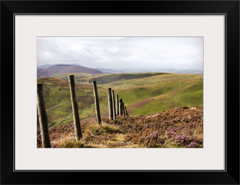 Photograph of a fence running though rolling hills in an Edinburgh countryside, Scotland, UK