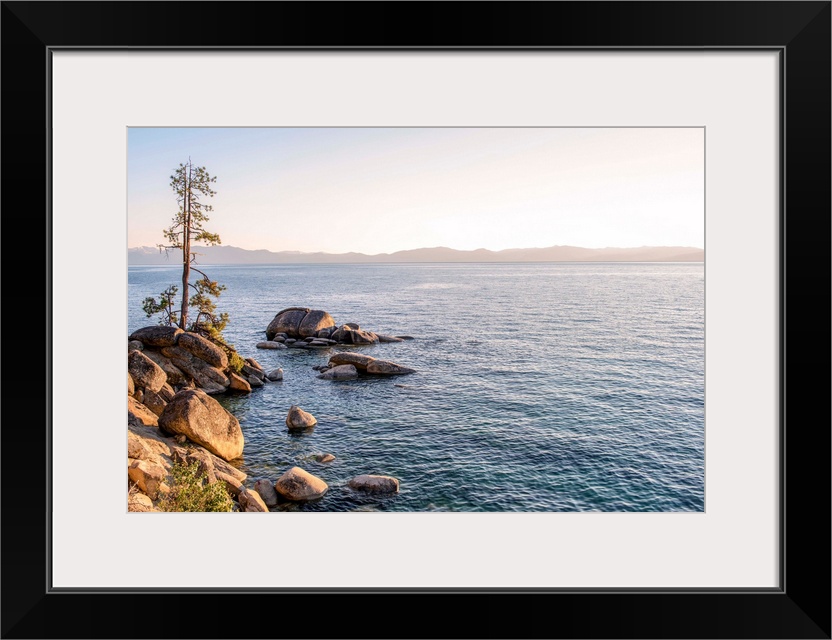 View of Lake Tahoe's rocky shore with mountain landscape in the background in California and Nevada.