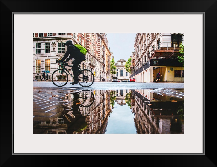 Photograph of a biker reflecting into a puddle in London, England.