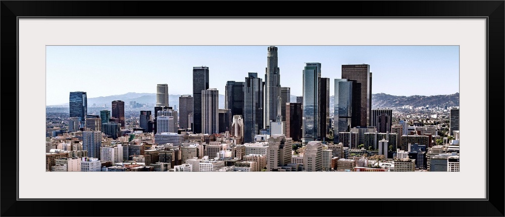 Panoramic photograph of skyscrapers and surrounding buildings of the Los Angeles skyline under a blue sky, California.