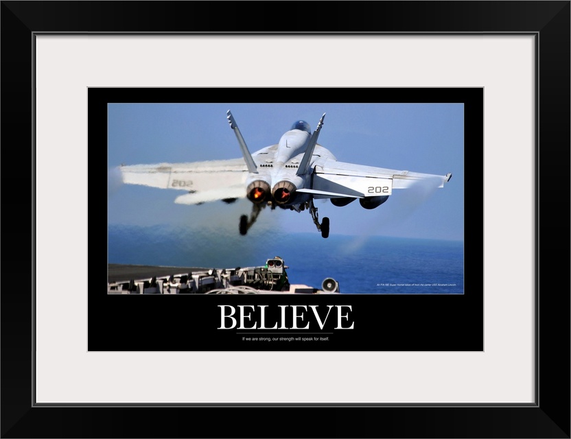 Large poster of a jet taking off from a ship with a black border around the picture and the word "Believe" under it.