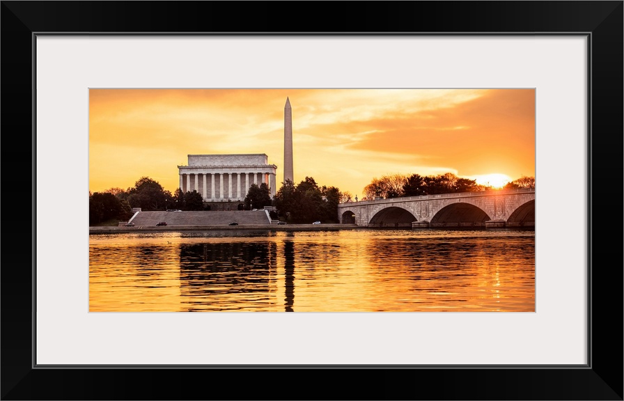 The Lincoln Memorial and Washington Monument seen from the Potomac River with orange clouds at dusk.