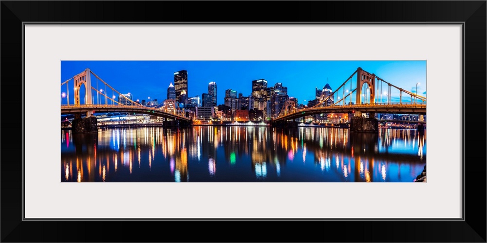 Panoramic photo of downtown Pittsburgh at night with the Rachel Carson Bridge and the Andy Warhol Bridge over the Alleghen...