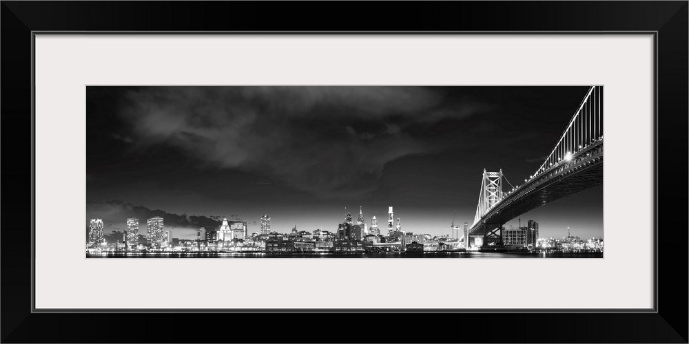 Panoramic photo of the Philadelphia city skyline at night, with the Benjamin Franklin Bridge on the right.