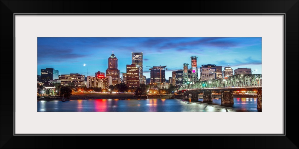 Panoramic photograph of a saturated Portland, Oregon skyline at sunset reflecting onto the Willamette River with a moon in...