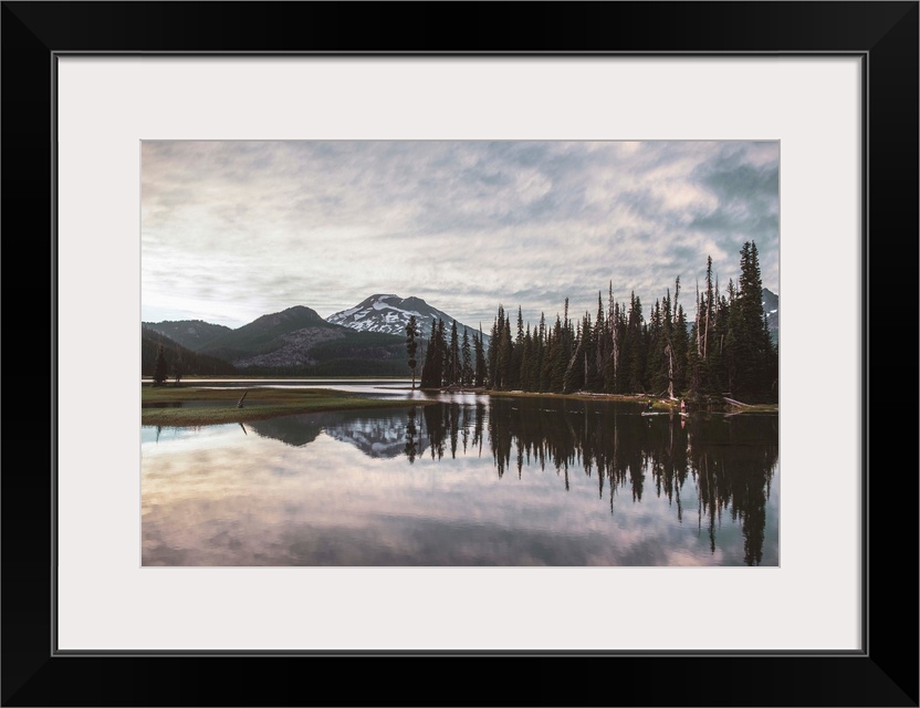 View of trees reflecting in Sparks Lake on a cloudy day in Deschutes National Forest, Oregon.