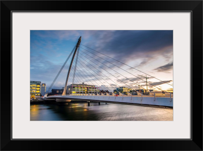 Photograph of the Samuel Beckett Bridge, a cable-stayed bridge in Dublin, Ireland going across the River Liffey, at sunset.