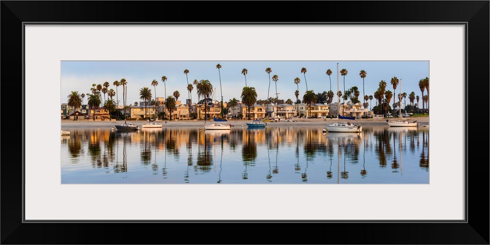 Panoramic photograph of beach houses, palm trees, and boats on the San Diego coast reflecting into the water.