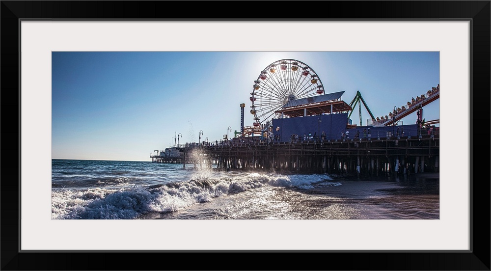 Panoramic photograph of the Santa Monica Pier in Los Angeles, California, with the sun setting right behind the Ferris Wheel.
