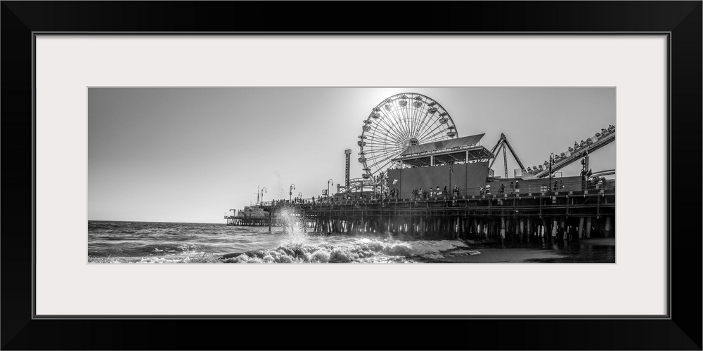 Panoramic photograph of the Santa Monica Pier in Los Angeles, California, with the sun setting right behind the Ferris Wheel.