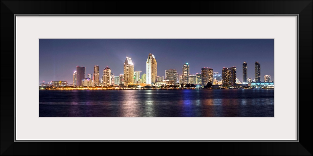 Panoramic photograph of the San Diego, California skyline lit up at night from across the water.